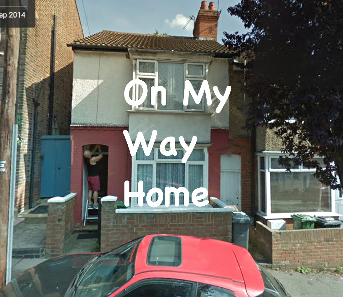 Photograph of a person fixing up a doorway of a semi-detached house formed of multiple cream- and salmon- coloured panels. A red car with a skylight parked outside. Caption in Comic Sans going across the centre of the image reads On My Way Home